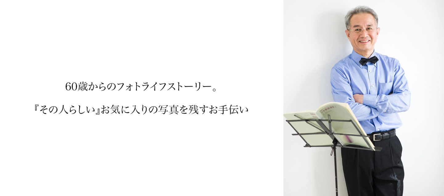 お気に入りの青いシャツと蝶ネクタイを身に着け、楽譜の前でほほえむ男性