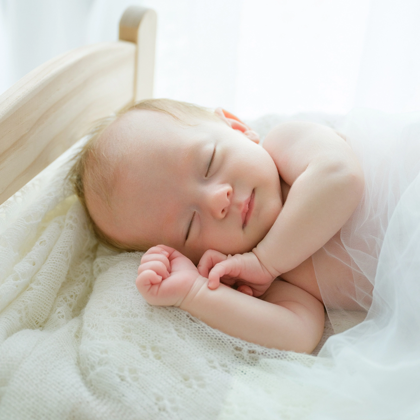 小さなベッドで眠る赤ちゃんのニューボーンフォト
