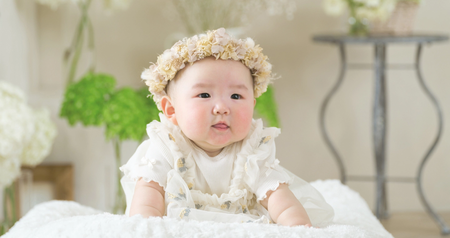 花冠と白い衣装で撮影した赤ちゃんの記念写真