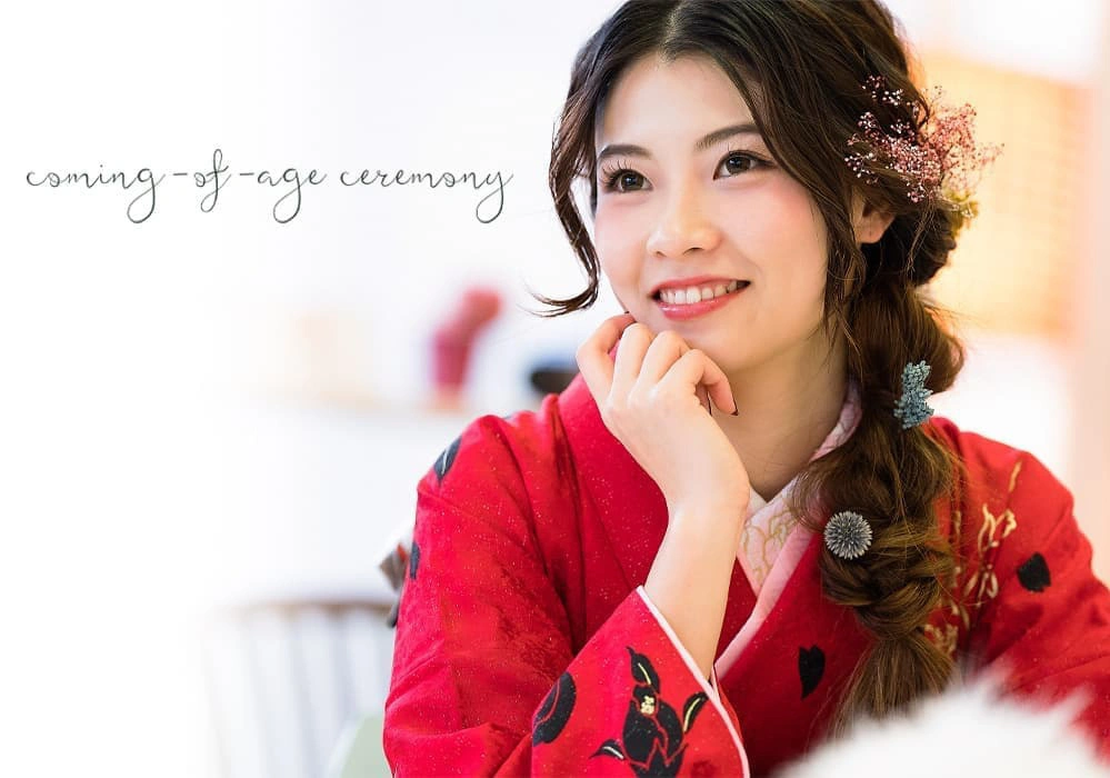 赤い振袖をまとい、笑顔を見せる二十歳の女性