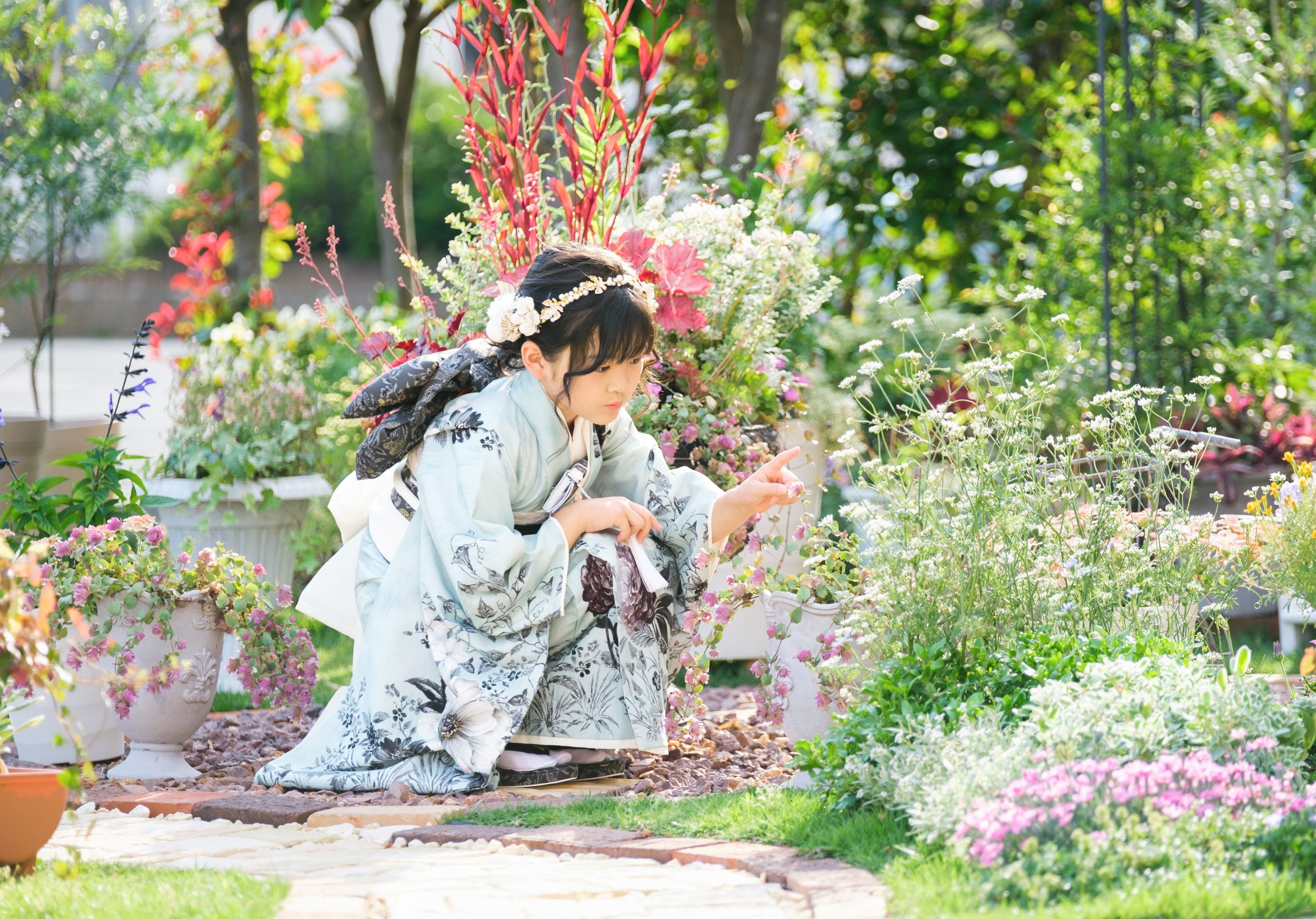 ガーデンの花に触れる七五三の自然な姿